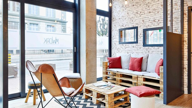 Un coin salon confortable avec un canapé et un fauteuil, une table basse en bois et un tapis à motifs.