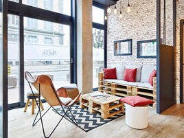 Un rincón acogedor con sofá y sillón, una mesa de centro de madera y una alfombra estampada.