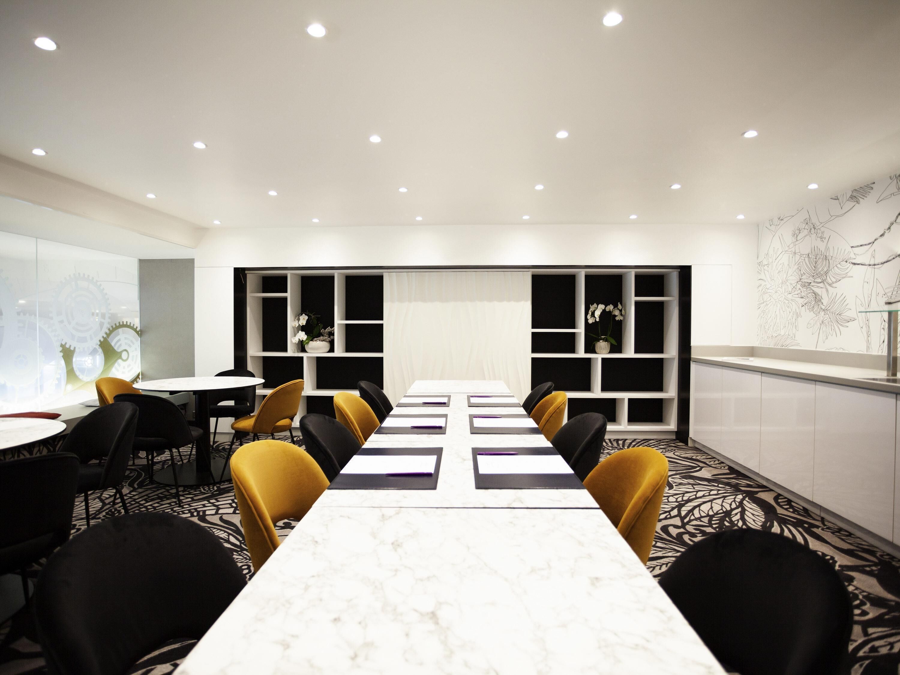 Une salle de conférence avec une longue table, des chaises et un tableau blanc.