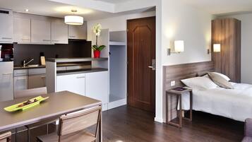 A modern hotel room with a wooden floor, a bed with white linens, a small bedside table, and a nightstand.