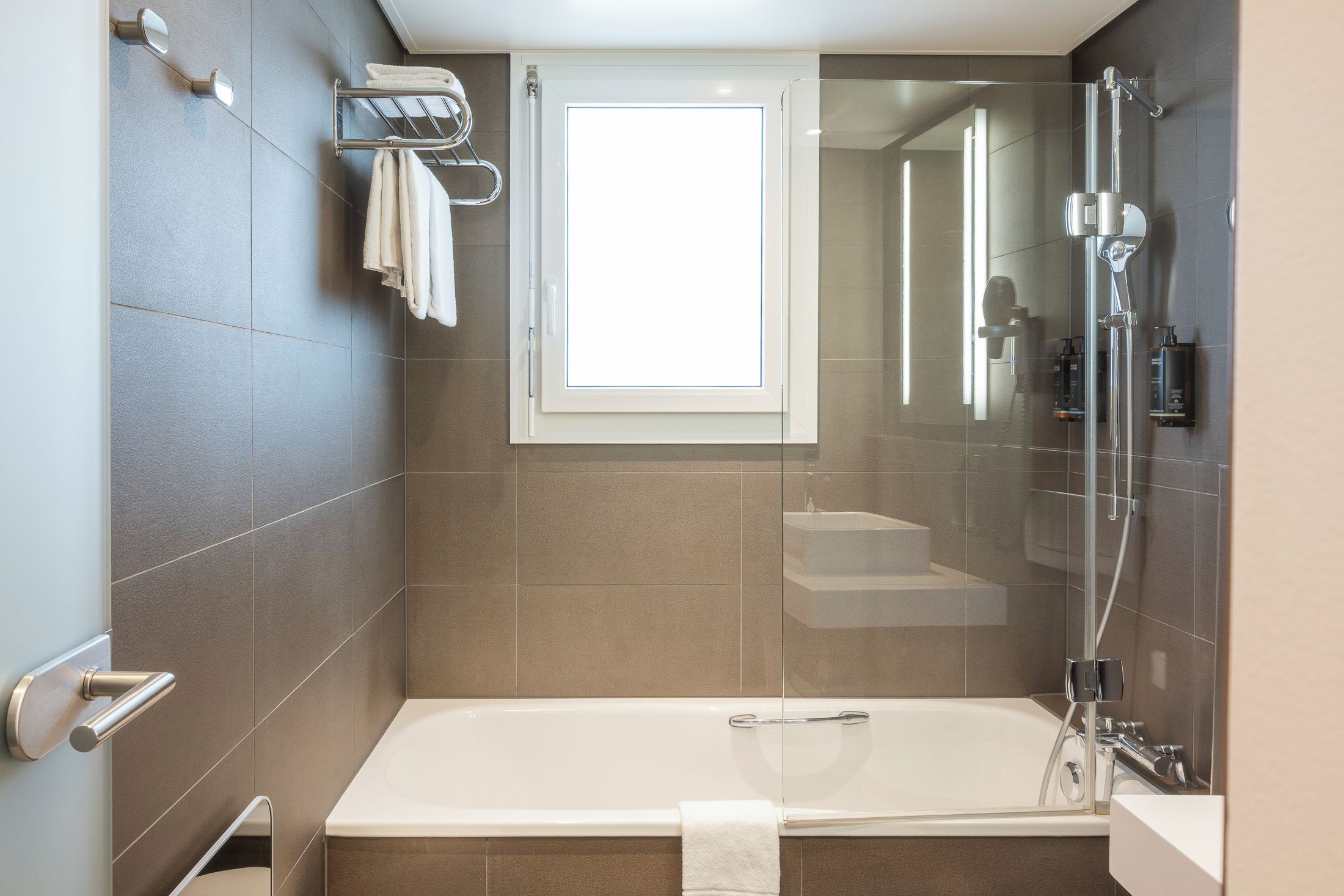 A modern bathroom with a bathtub, a shower area, and a window.