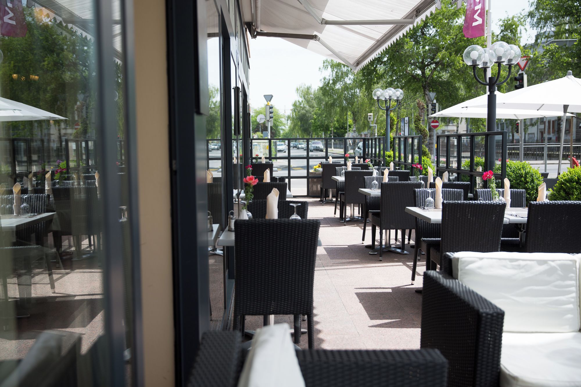 An outdoor seating area with tables and chairs, umbrellas, and street lamps.