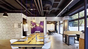 Une salle de conférence avec une longue table, des chaises blanches et des lampes suspendues.