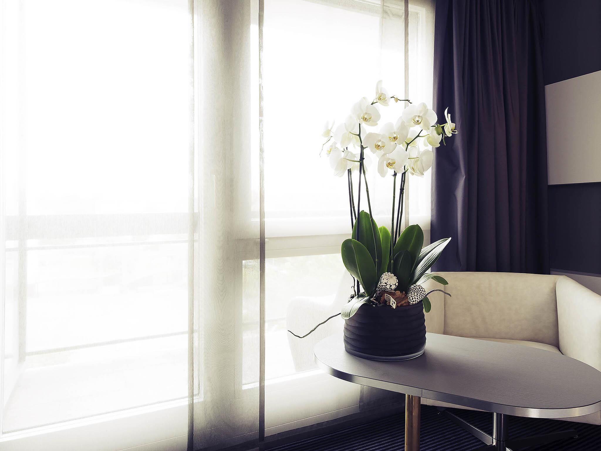 Una habitación moderna con una mesa redonda, una orquídea en maceta y un sofá.