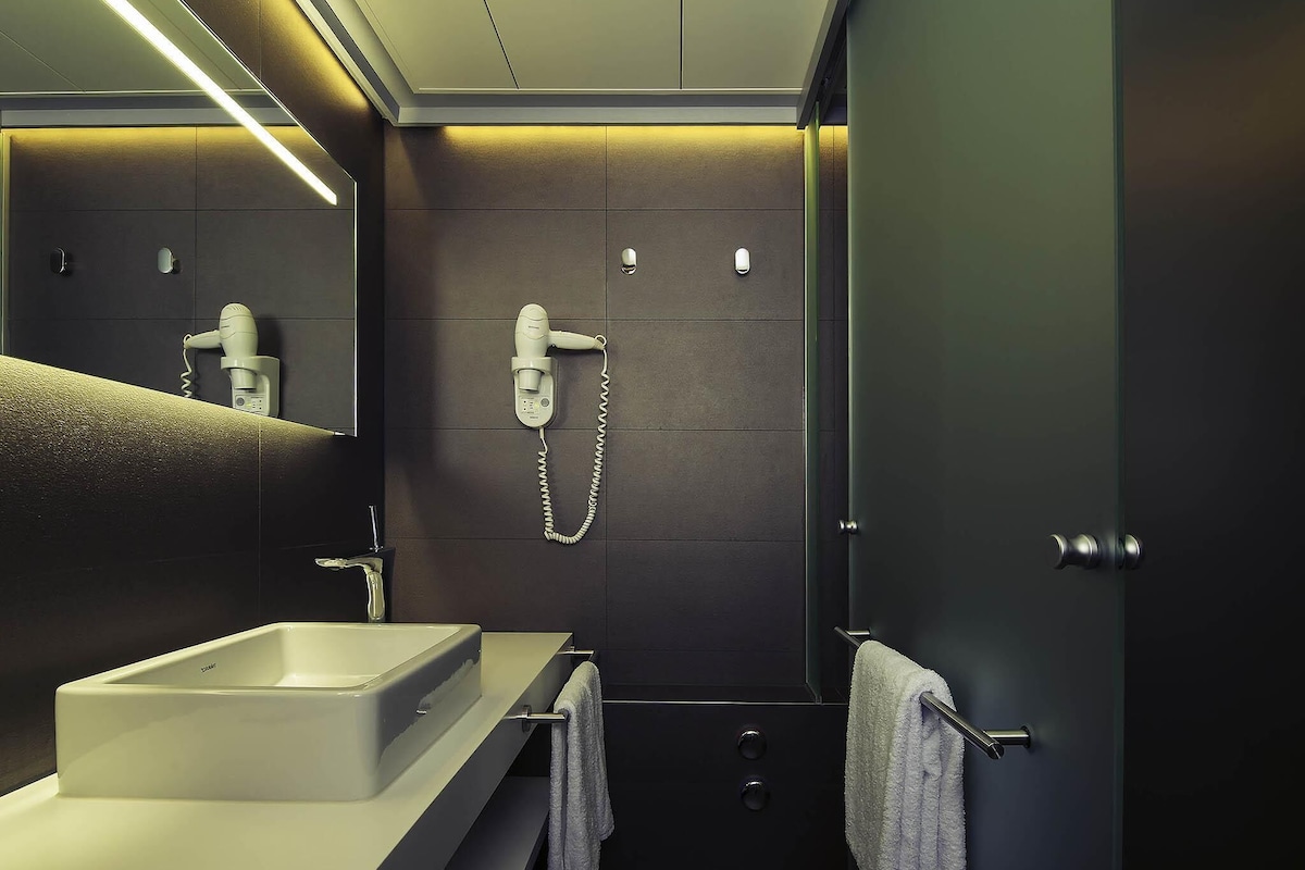 A modern bathroom with a built-in sink, a hairdryer, and a towel rack.