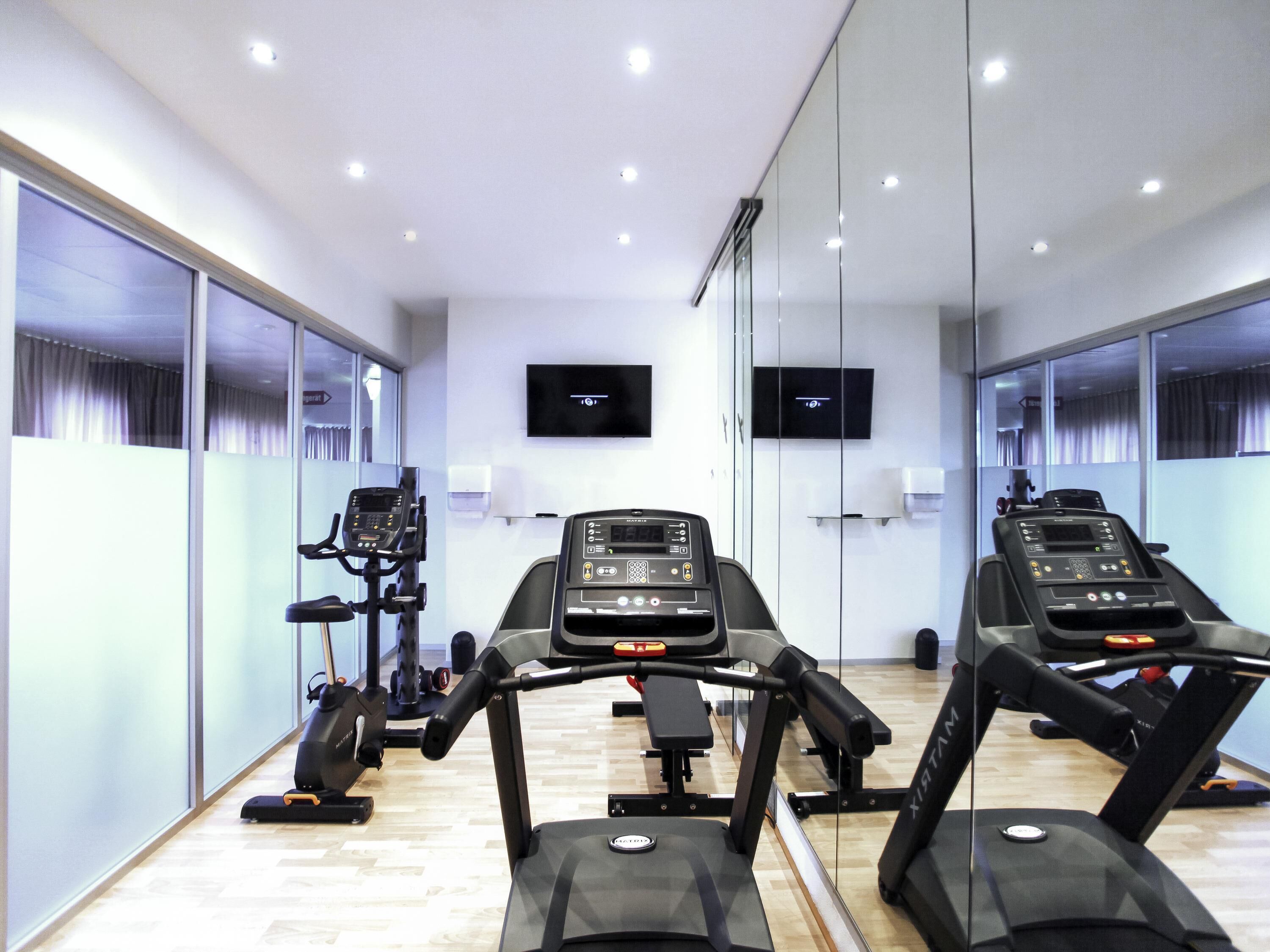 A gym with treadmills, exercise bikes, and a mirrored wall.