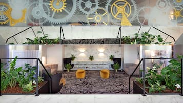 Un hall d’entrée au design moderne, doté d’un sol en marbre, d’un espace de détente central avec un canapé et un pouf, et d’un mur décoratif orné d’engrenages mécaniques.