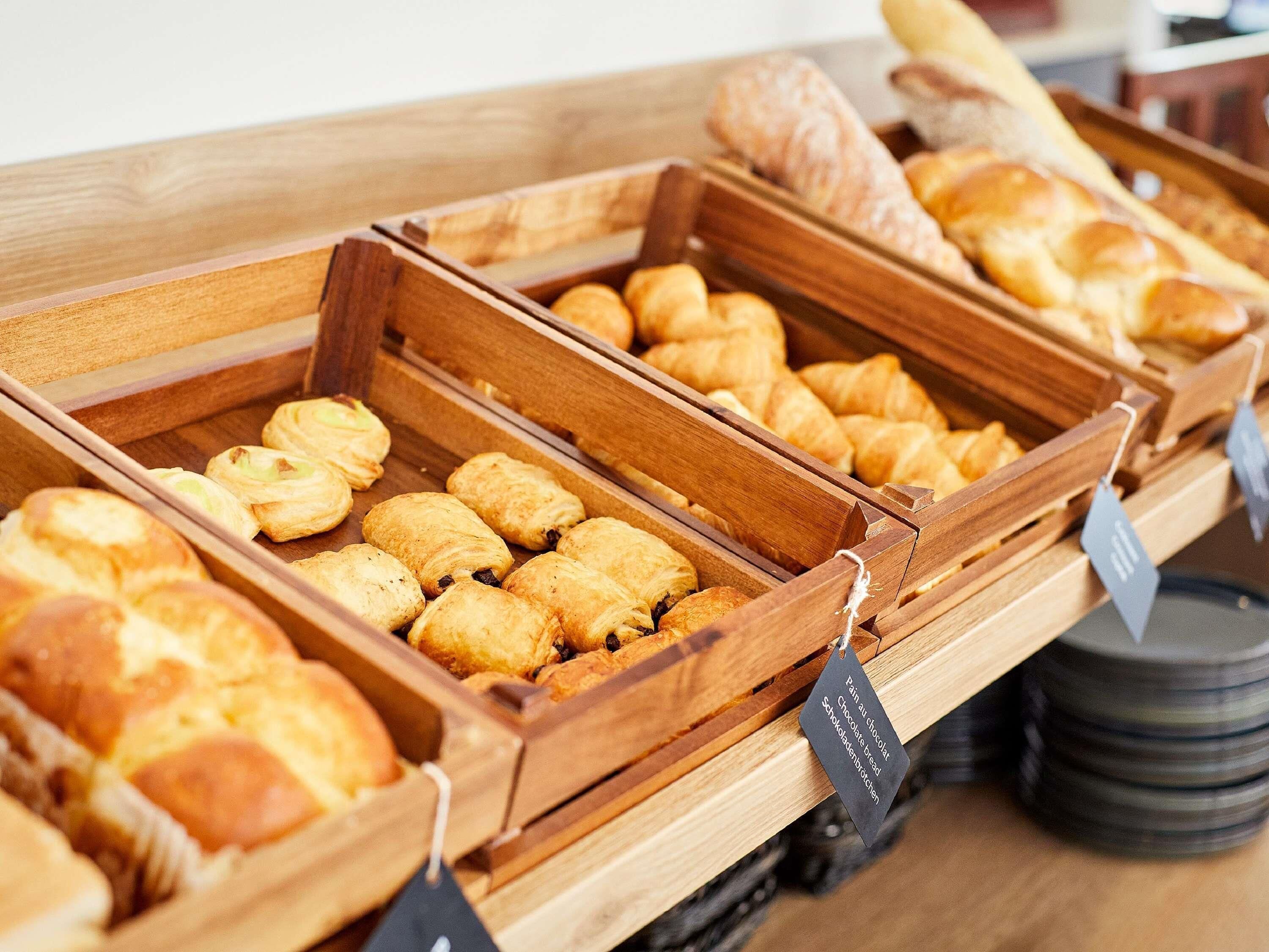 A bakery display with various baked goods in wooden trays.