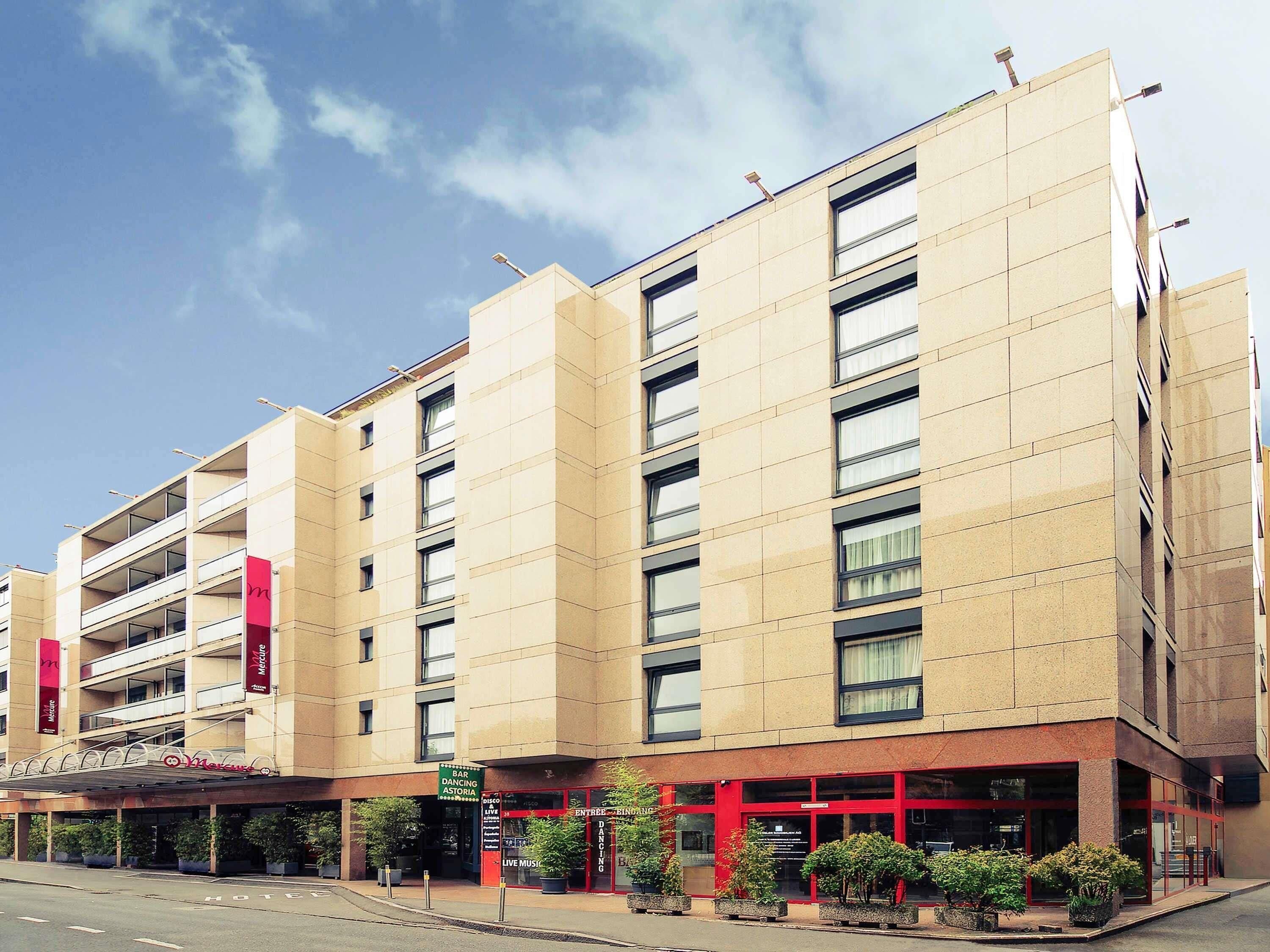 Et hotel med flere etager, moderne facade, altaner og en rød indgang.