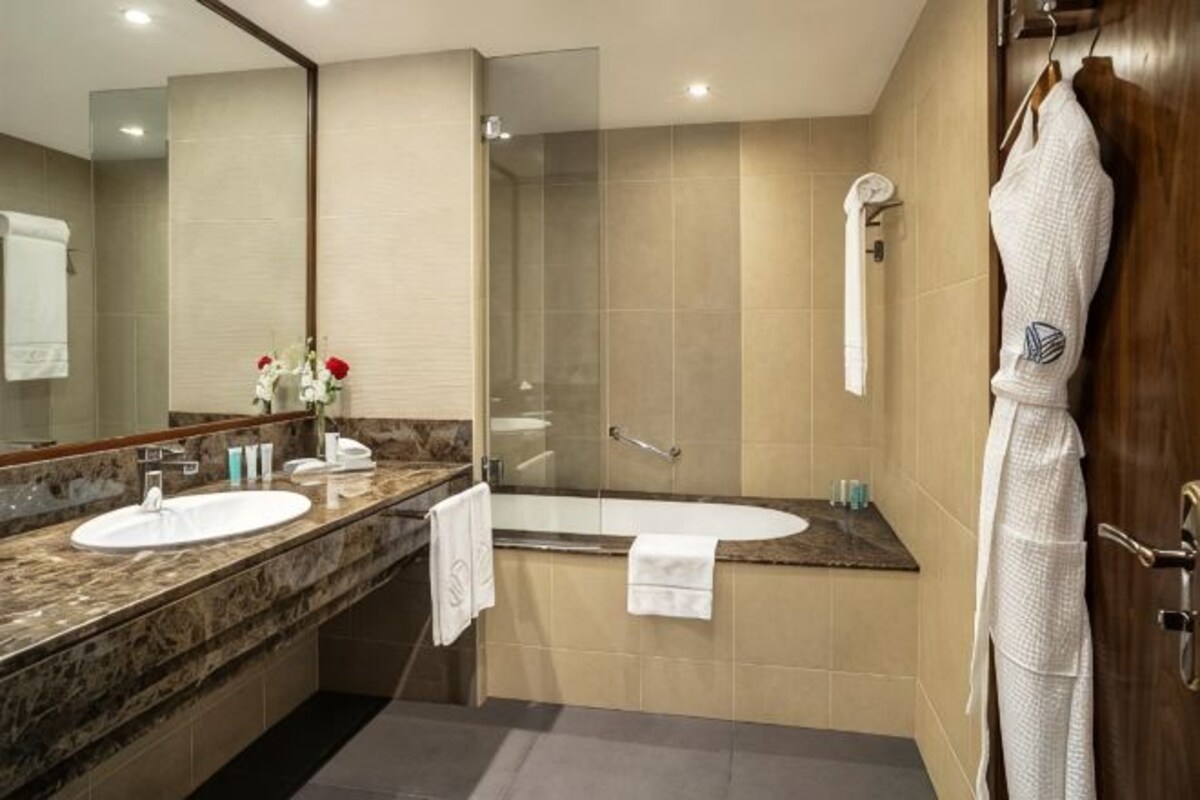 A bathroom with two sinks, a shower, and a robe hanging on the wall.