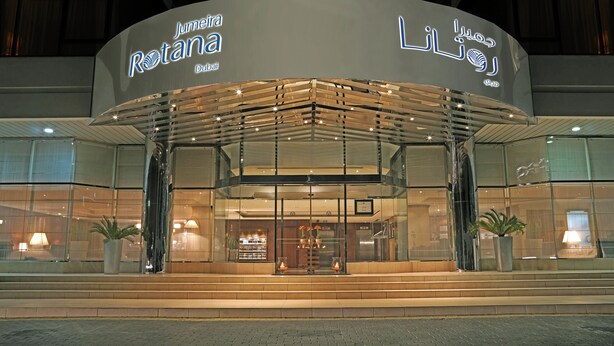 A modern hotel entrance with glass doors and a covered walkway.