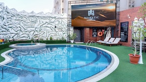 A swimming pool with a view of a building, a brick wall, and lounge chairs.