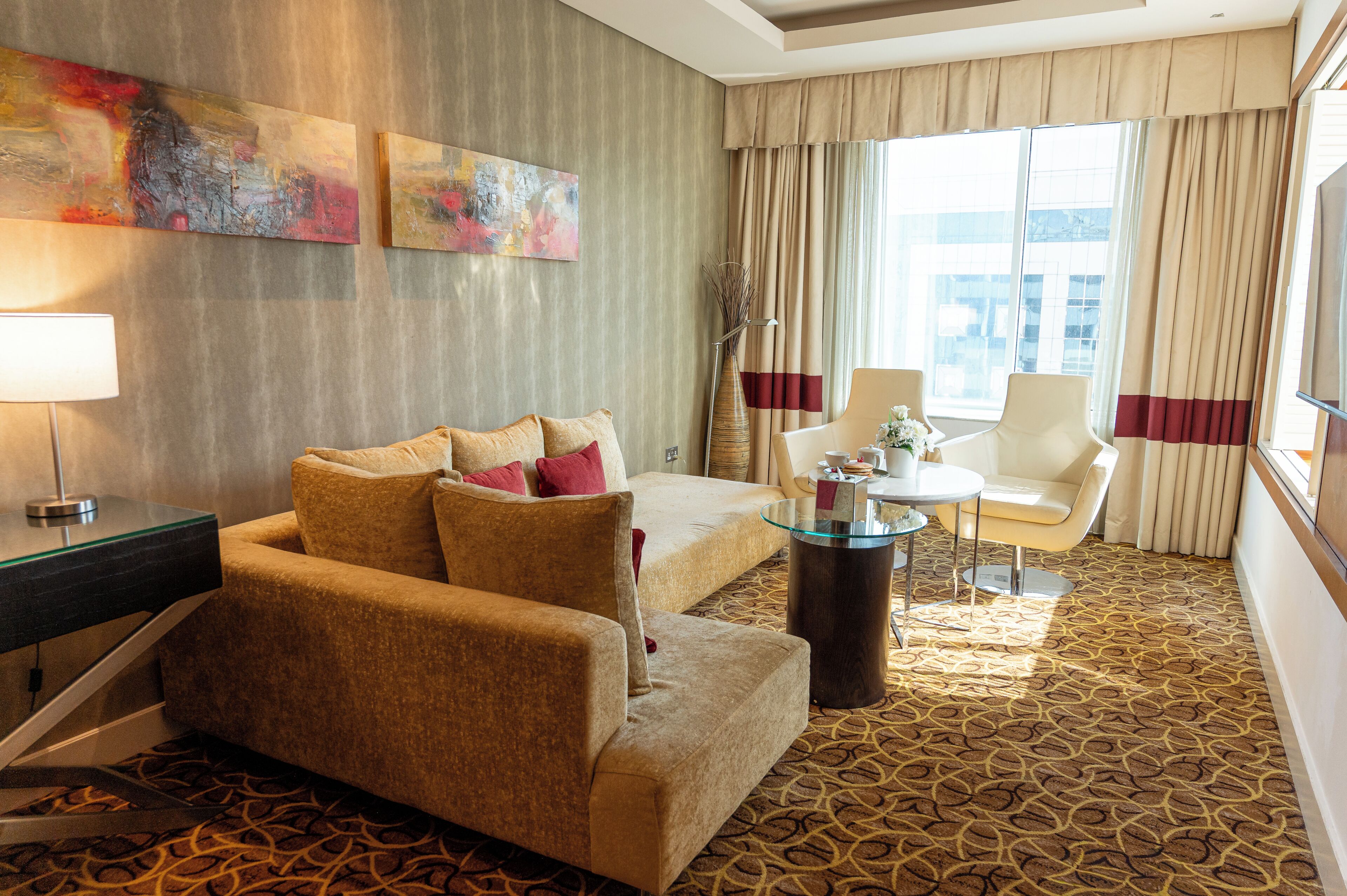 Ein Hotelzimmer mit einer Couch, einem Sessel, einem kleinen Tisch und einem Kunstwerk an der Wand.