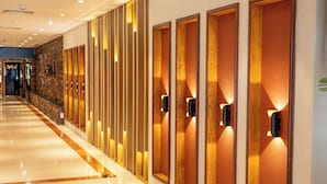 A hotel corridor with a polished marble floor, wooden paneling, and illuminated wall sconces.