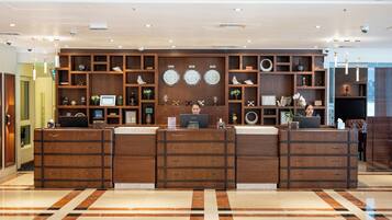 A reception desk with a laptop, wooden cabinets, and wall clocks.