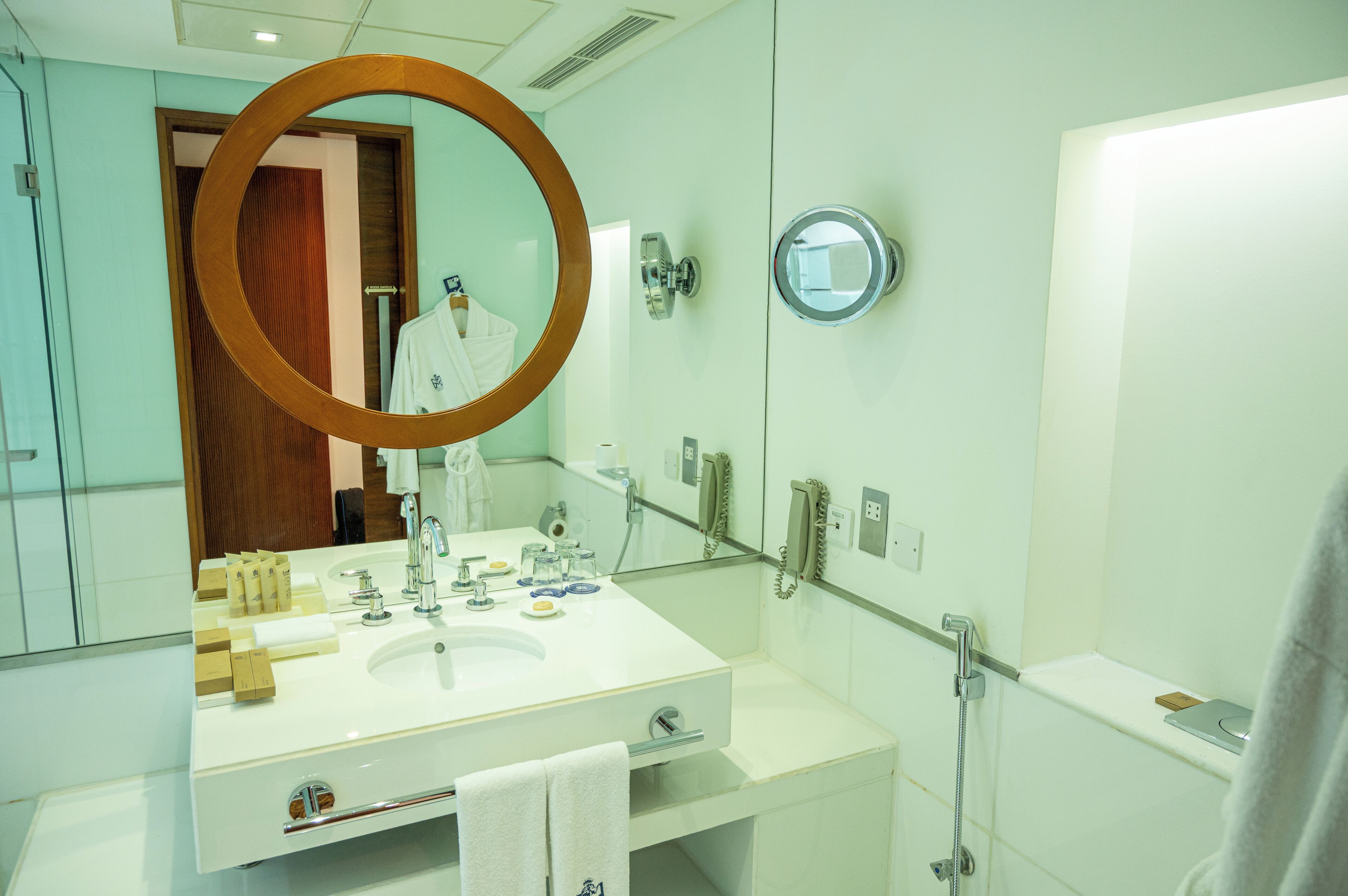 Une salle de bain moderne avec un grand miroir, un lavabo, un porte-serviettes et un espace douche.