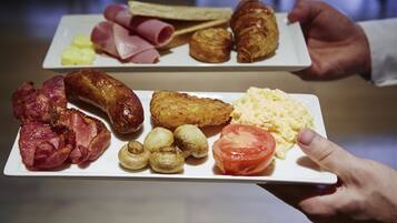 A breakfast plate with ham, sausages, eggs, and a croissant.