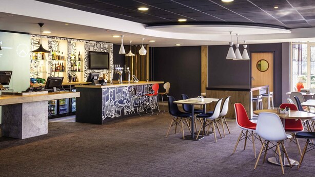 Un espace bar moderne doté d’un comptoir, de sièges et d’un écran de télévision.