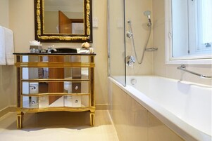 Ein Badezimmer mit goldfarbenem Waschtisch, einem großen Spiegel, einer Badewanne und einer Dusche.