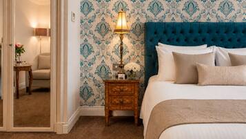 A bedroom with a tufted headboard, a bedside table with a lamp, and a mirror.