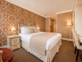 A hotel room with a large bed, bedside tables, a desk, and a chair.