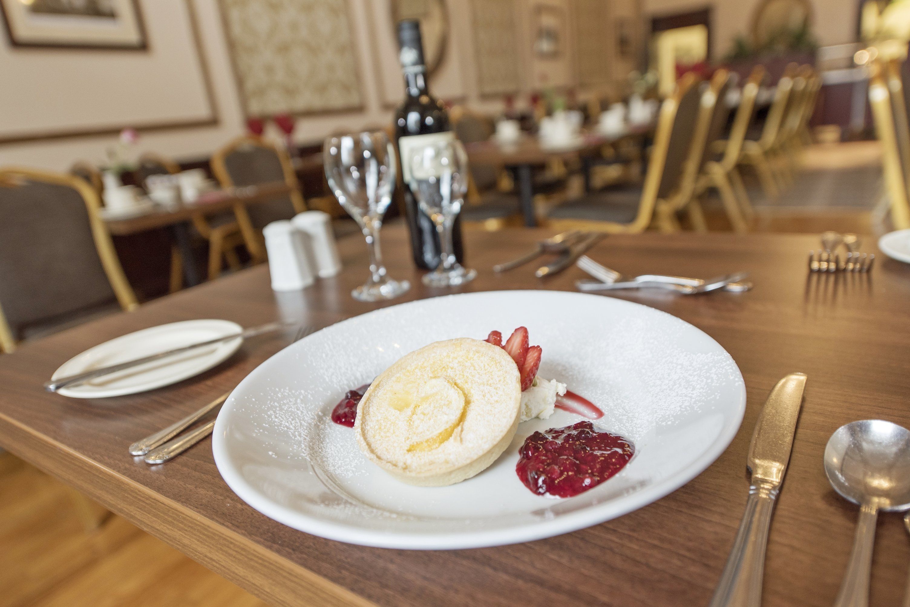 A dessert plate with a cake and berries on a table in a restaurant.