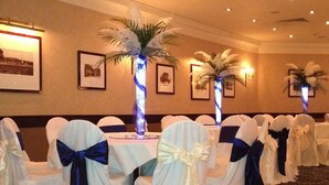 A conference room with rows of tables, each with a white tablecloth and chairs with blue sashes. - Salutation Hotel (Perth)