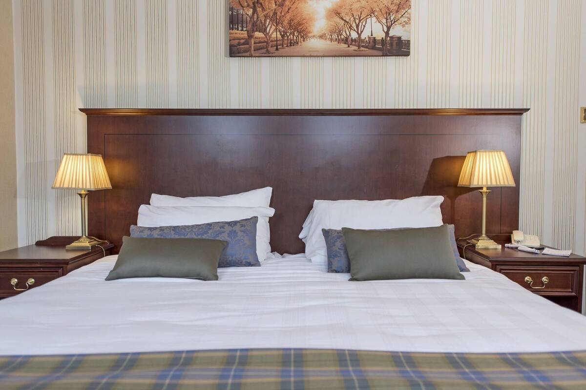 A hotel room with a large bed, two bedside tables with lamps, and a framed picture on the wall.