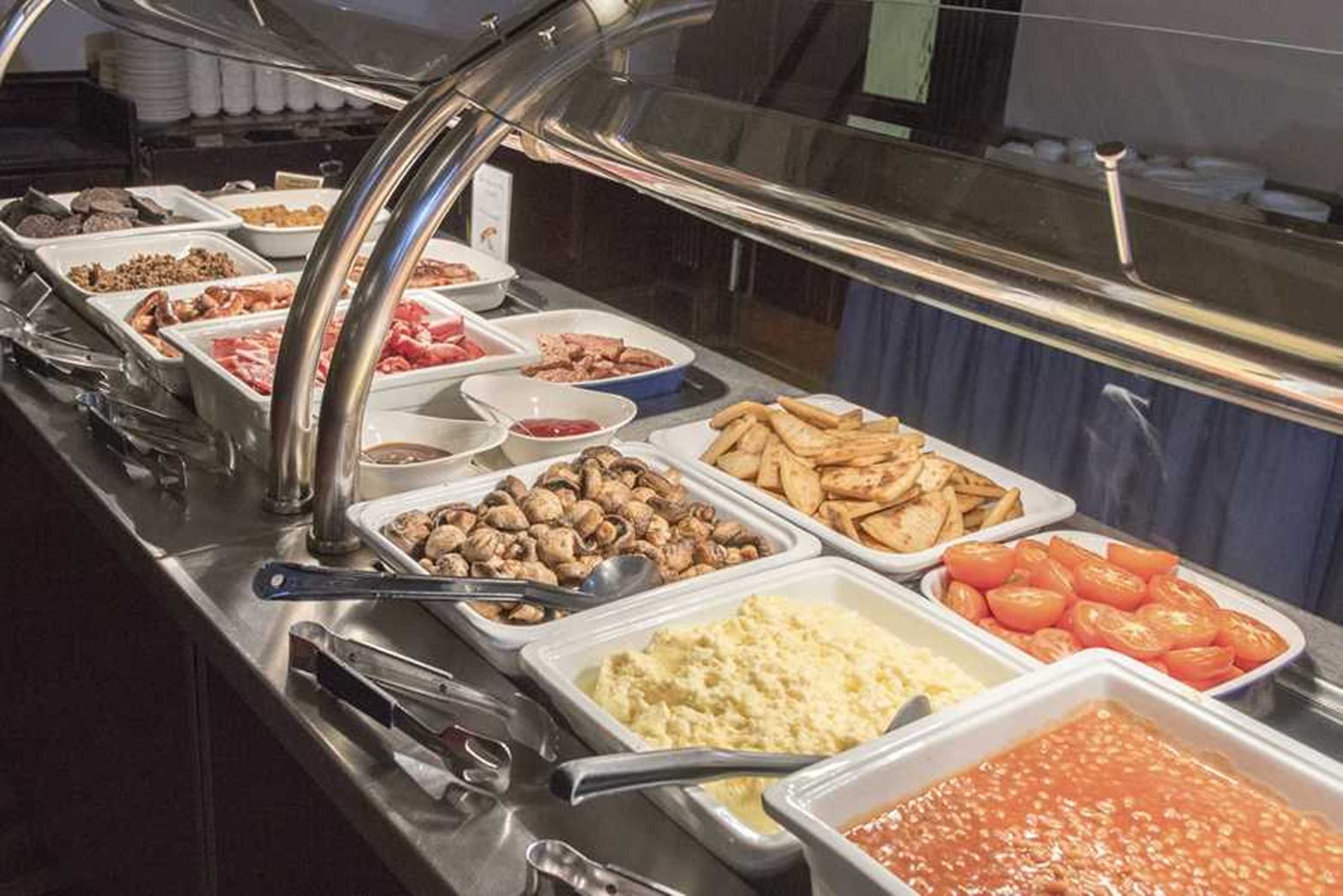 Un bufé con diversos alimentos, incluyendo carnes, quesos y verduras.