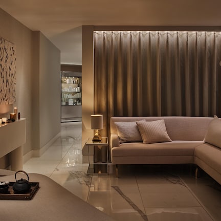 A modern living room with a beige sofa, a side table with a lamp, and a decorative tray with a teapot.