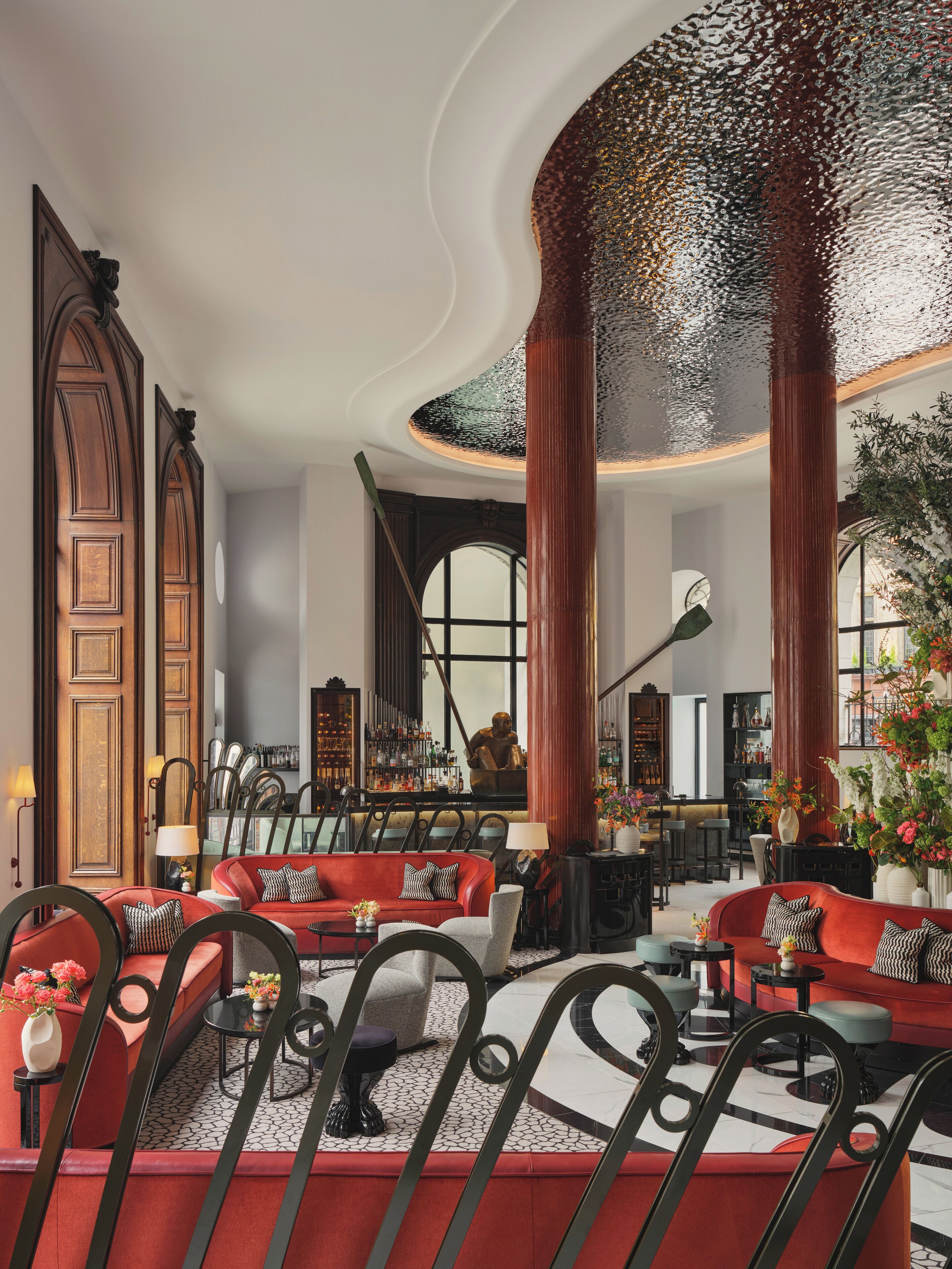 A spacious lobby with a high ceiling, large windows, and a bar area.