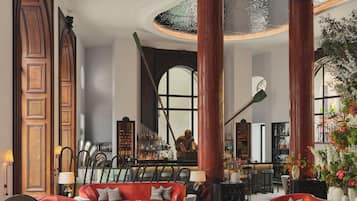 A spacious lobby with a high ceiling, large windows, and a bar area.