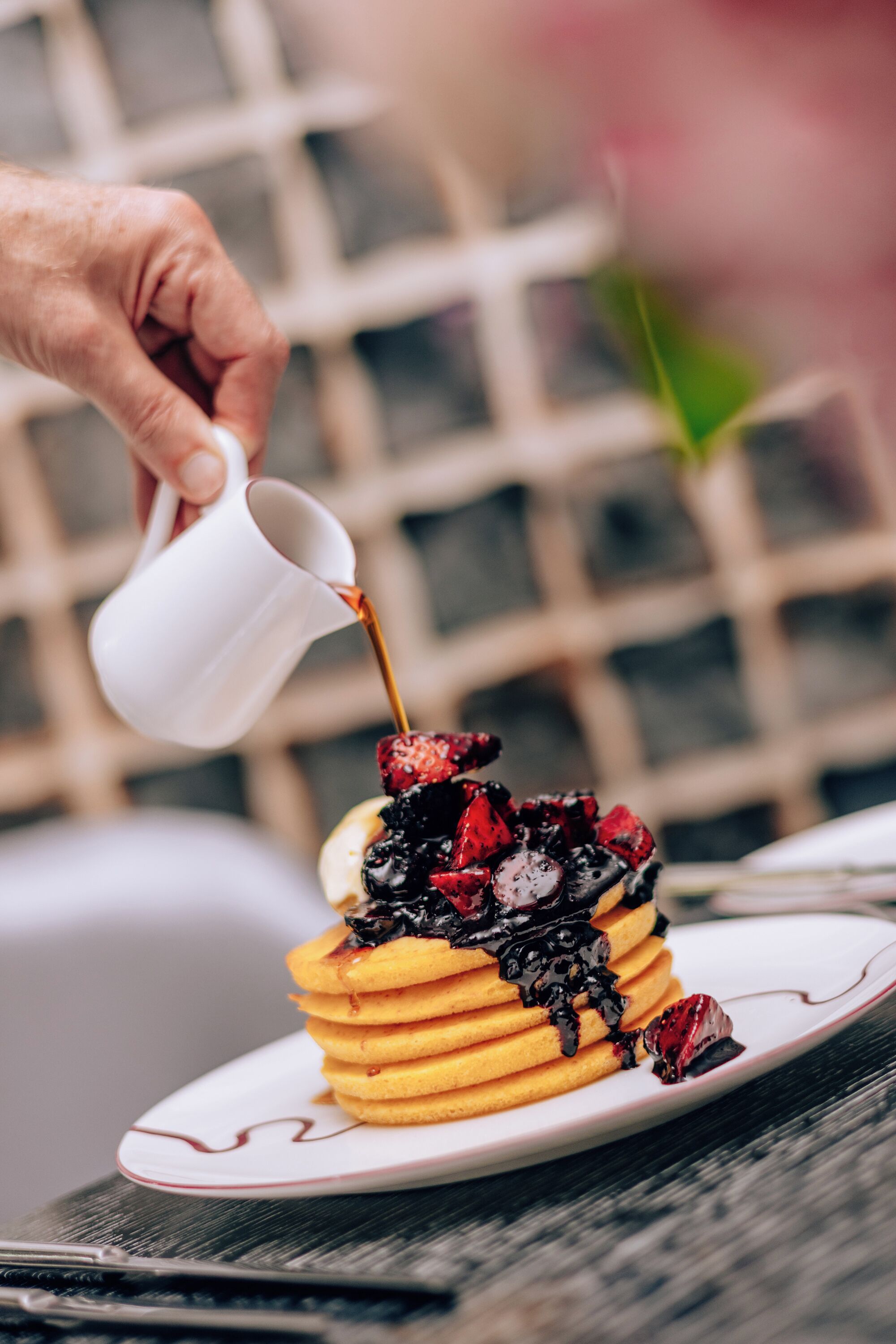 A stack of pancakes with berries and syrup on a plate.