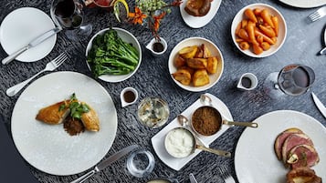 Una mesa dispuesta con diversos platos, incluyendo patatas asadas, zanahorias y un guiso de carne, junto con varias copas de vino.