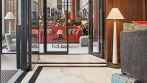 Un vestíbulo amplio con un sofá rojo, una mesa de centro y un ventanal que ofrece vistas a una zona de bar.