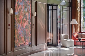 A modern lobby with a large abstract painting, a red sofa, and a white armchair.