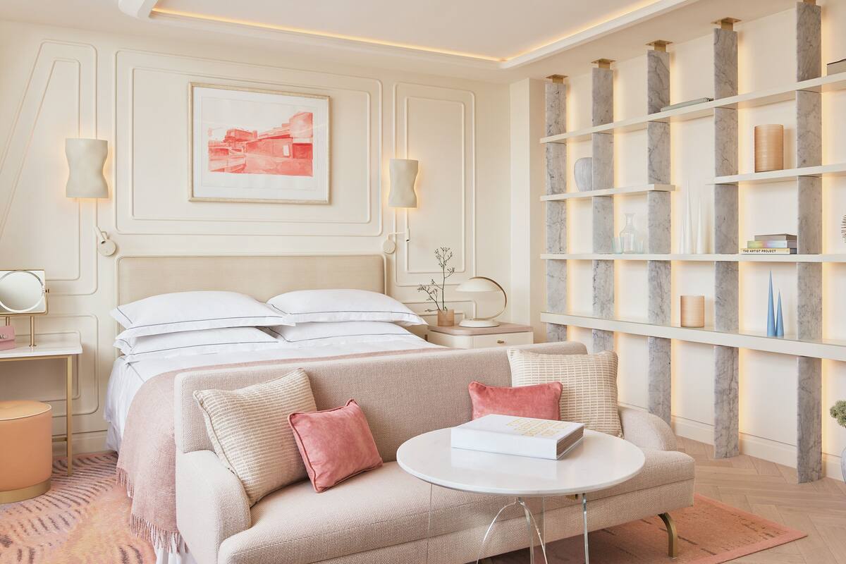 A modern bedroom with a bed, a sofa, a bedside table, a nightstand, and a bookshelf.