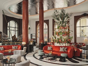 A spacious lobby with a red sofa, grey armchairs, and a large floral arrangement.