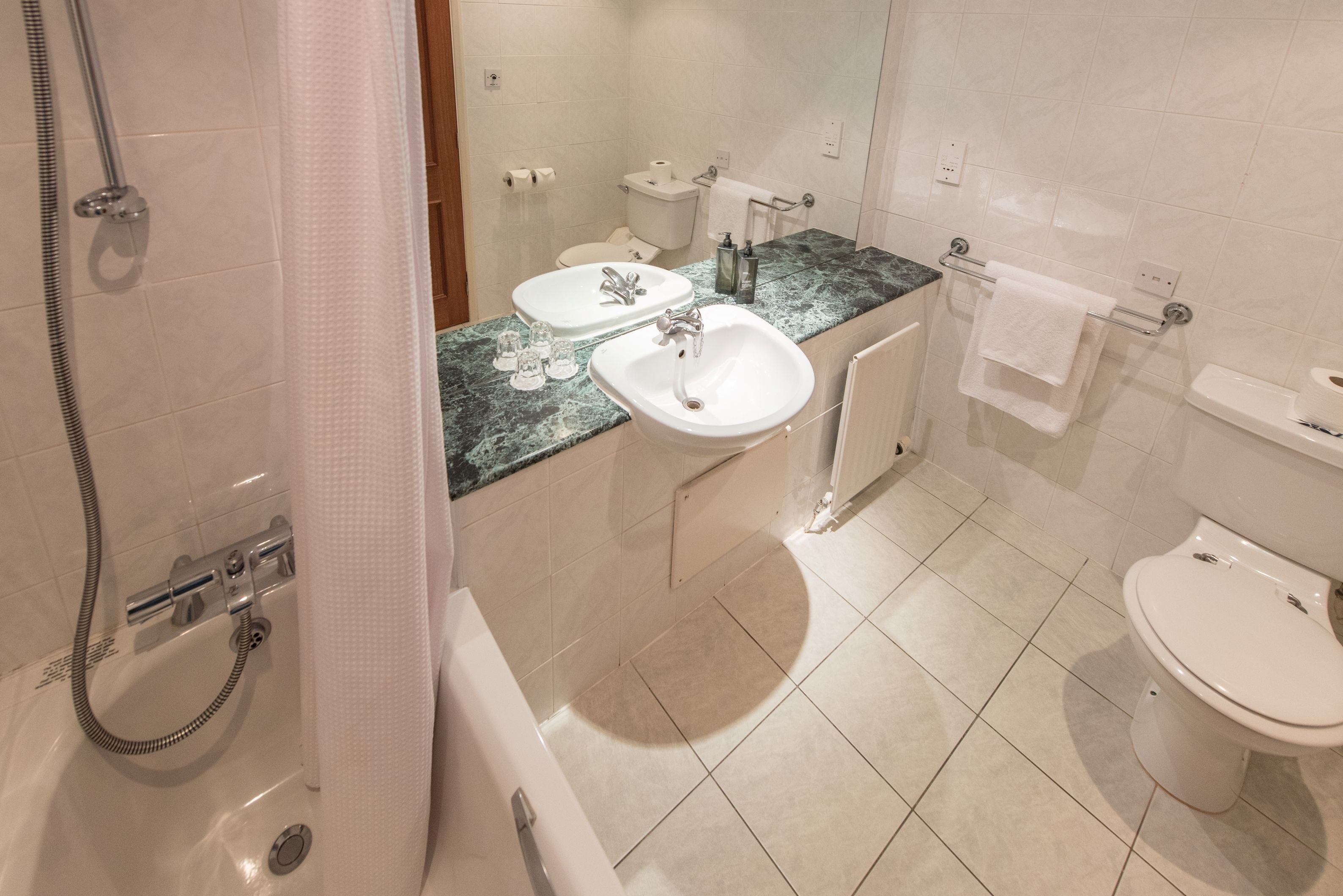 Un baño con bañera, dos lavamanos, inodoro y ducha.