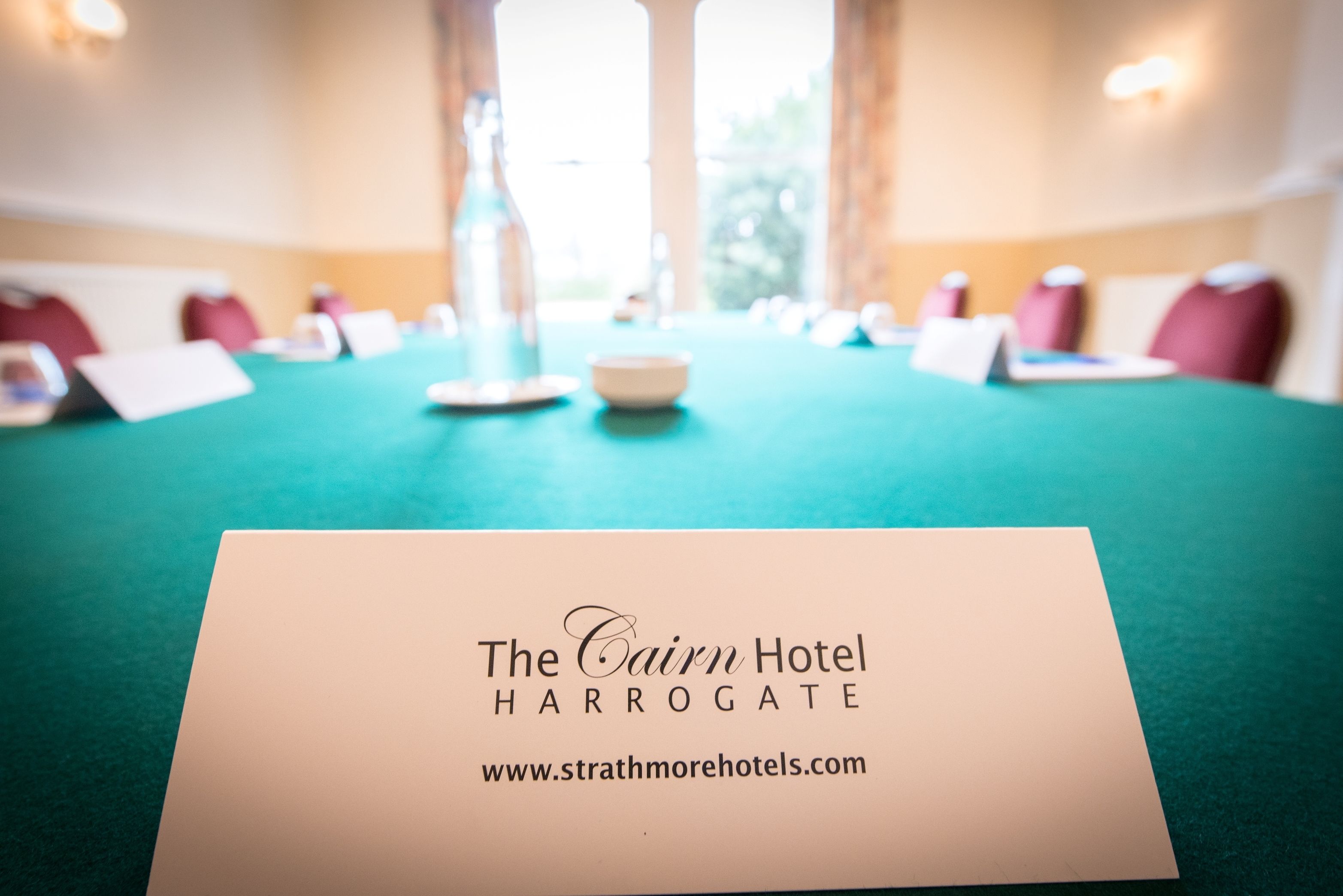 Una taula de conferències amb un cartell que diu "The Cairn Hotel Harrogate" i una adreça web.