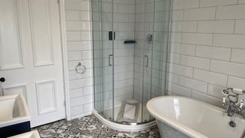 Un baño con ducha de vidrio, bañera independiente y baldosas de suelo estampadas.