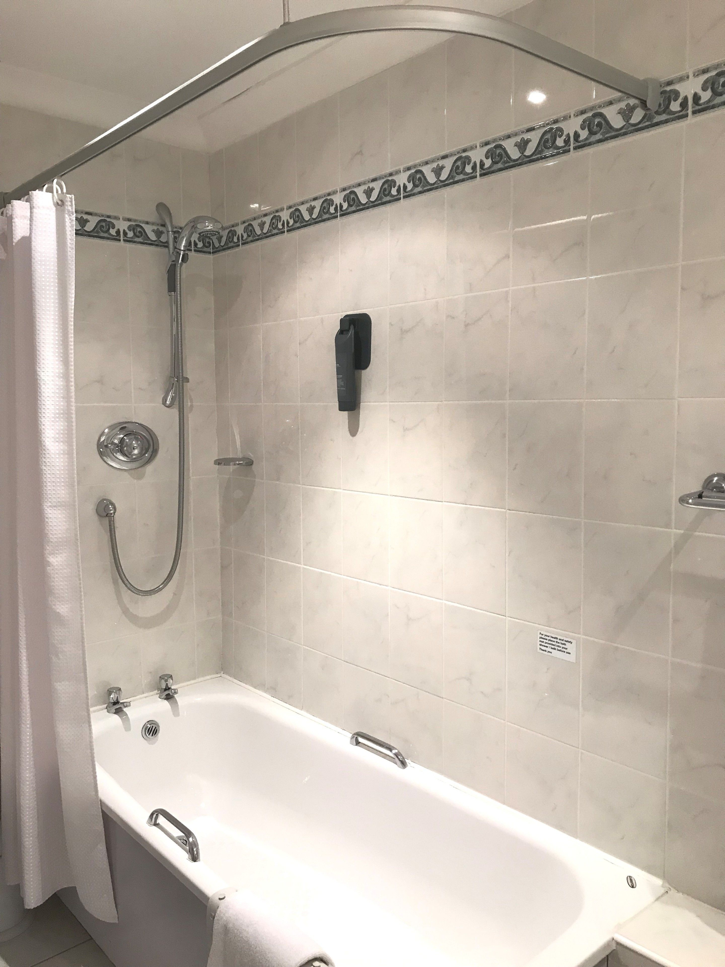 A bathroom with a bathtub, a shower, and a towel rack.