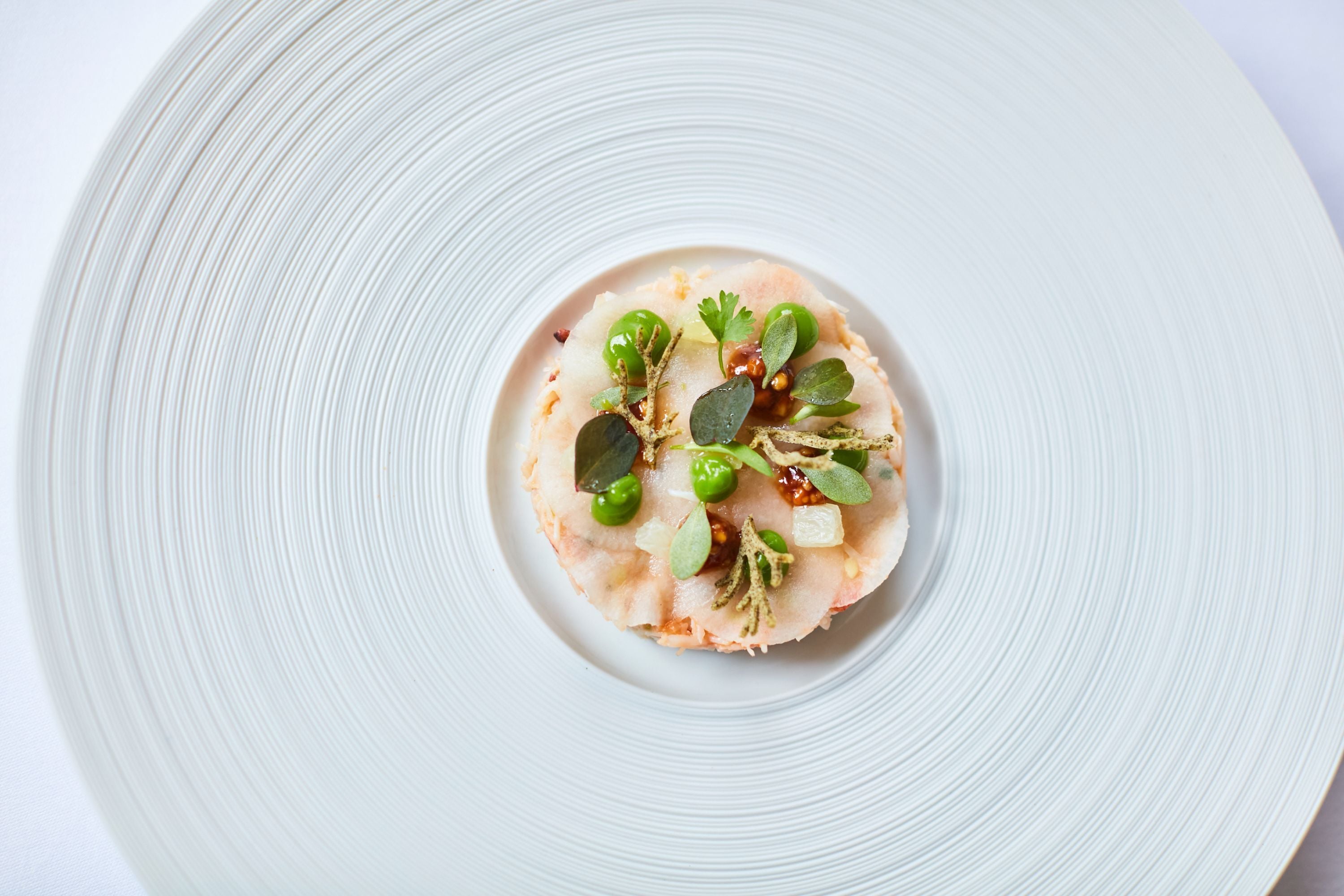 A white plate with a food item on a white textured surface.