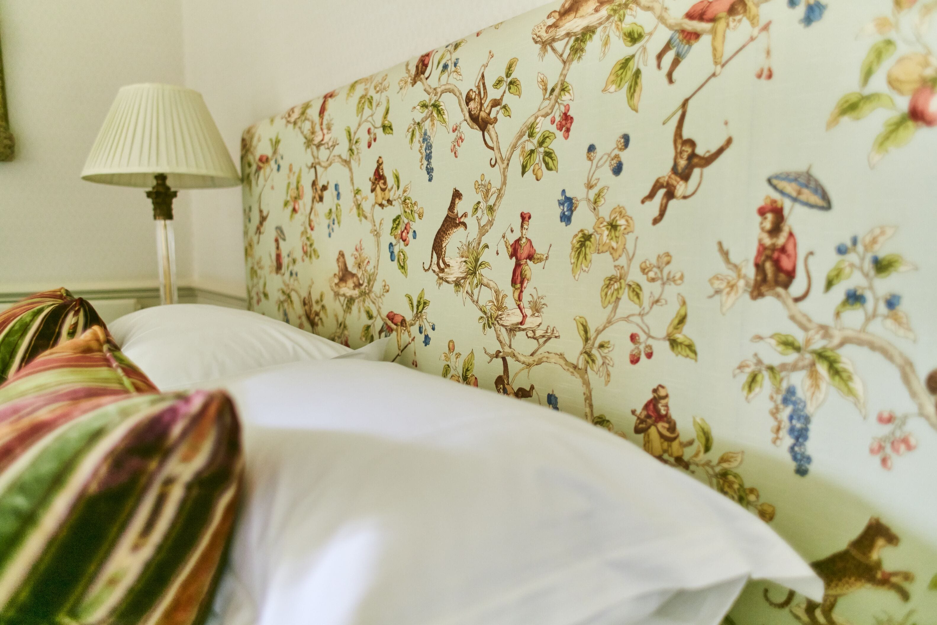 Cama com cabeceira estampada com flores e almofadas listradas.