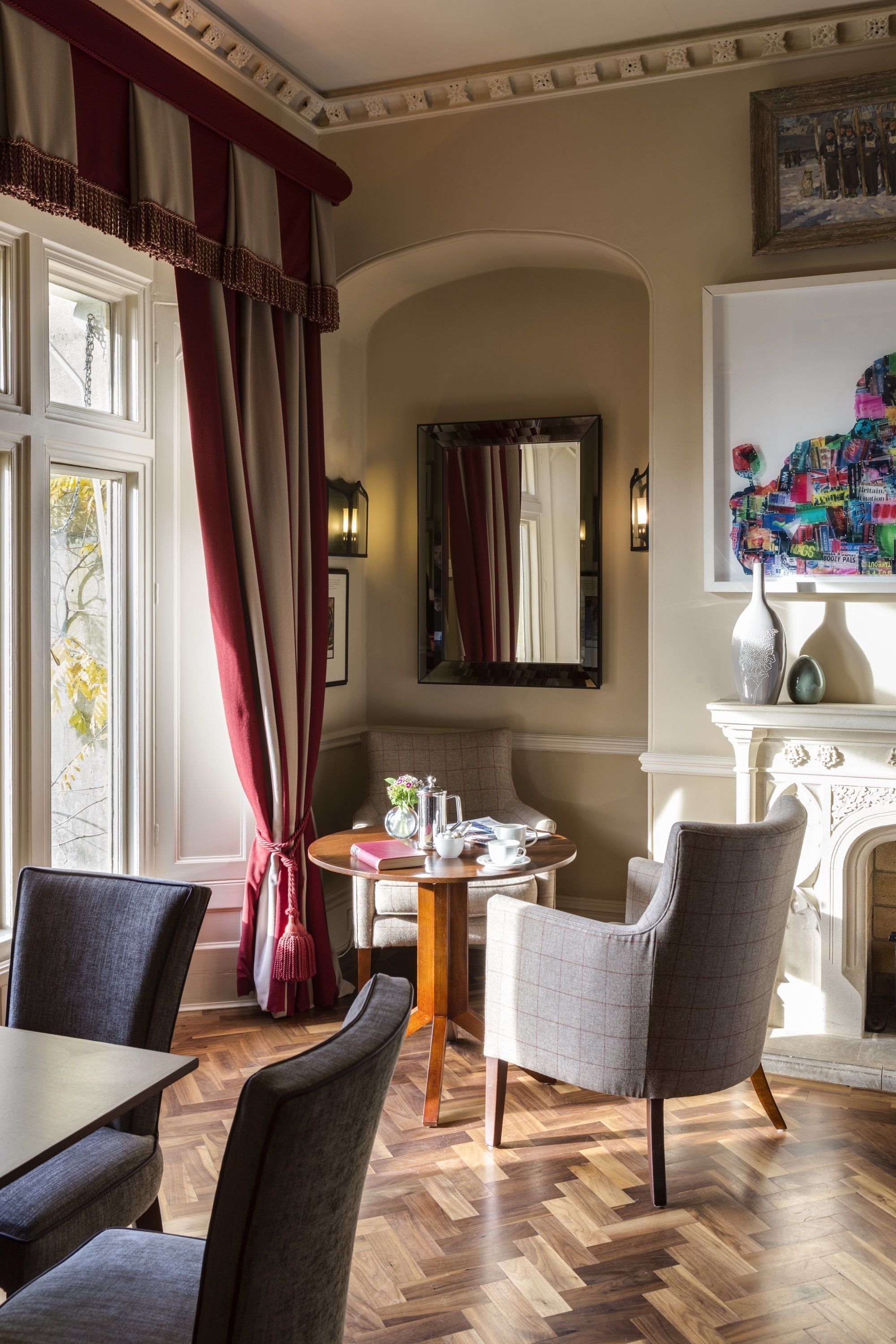 A dining area with a wooden herringbone floor, a round table, and two upholstered chairs.