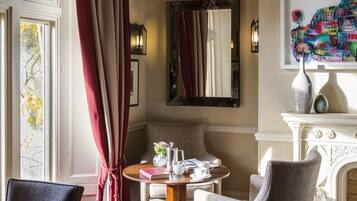 A dining area with a wooden herringbone floor, a round table, and two upholstered chairs.