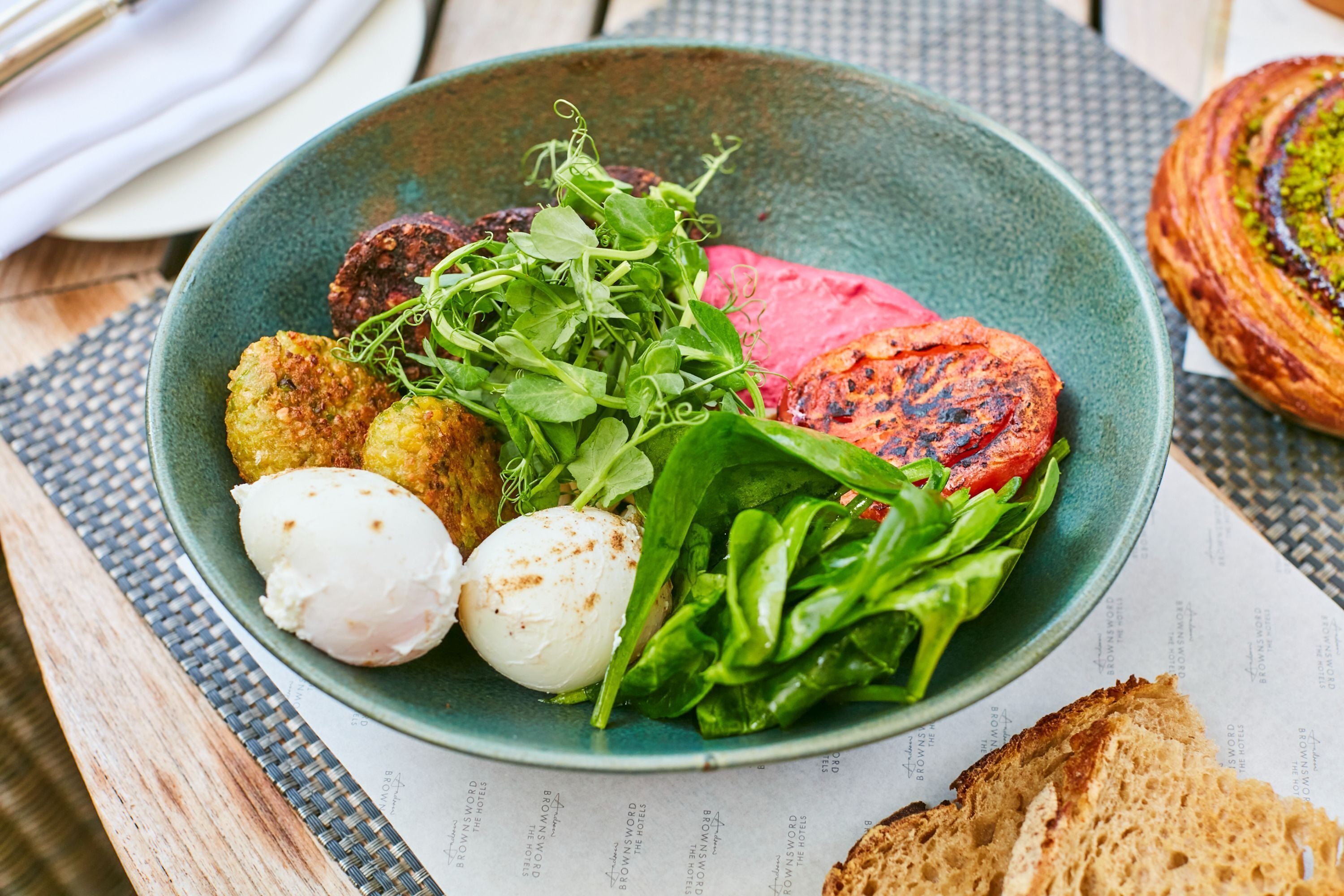 A plate with various food items including a grilled patty, a poached egg, and some greens.