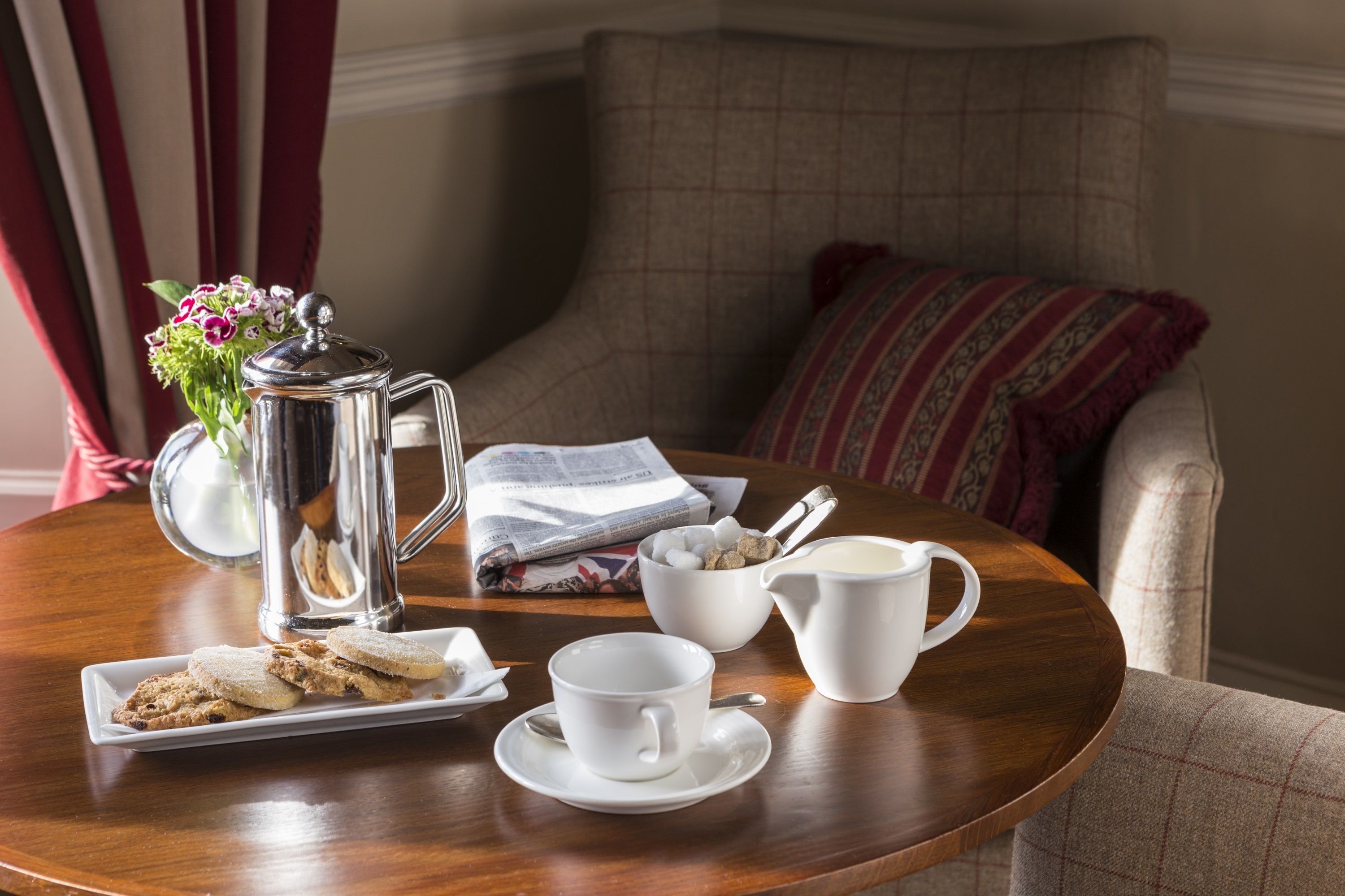 Une table à manger avec un pichet, un bol de biscuits, une tasse et une soucoupe.
