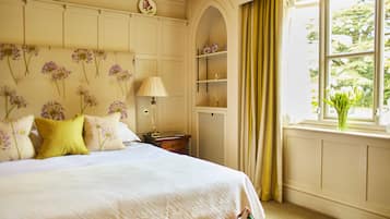 A neatly arranged bedroom with a bed, bedside table, lamp, and a window with curtains.