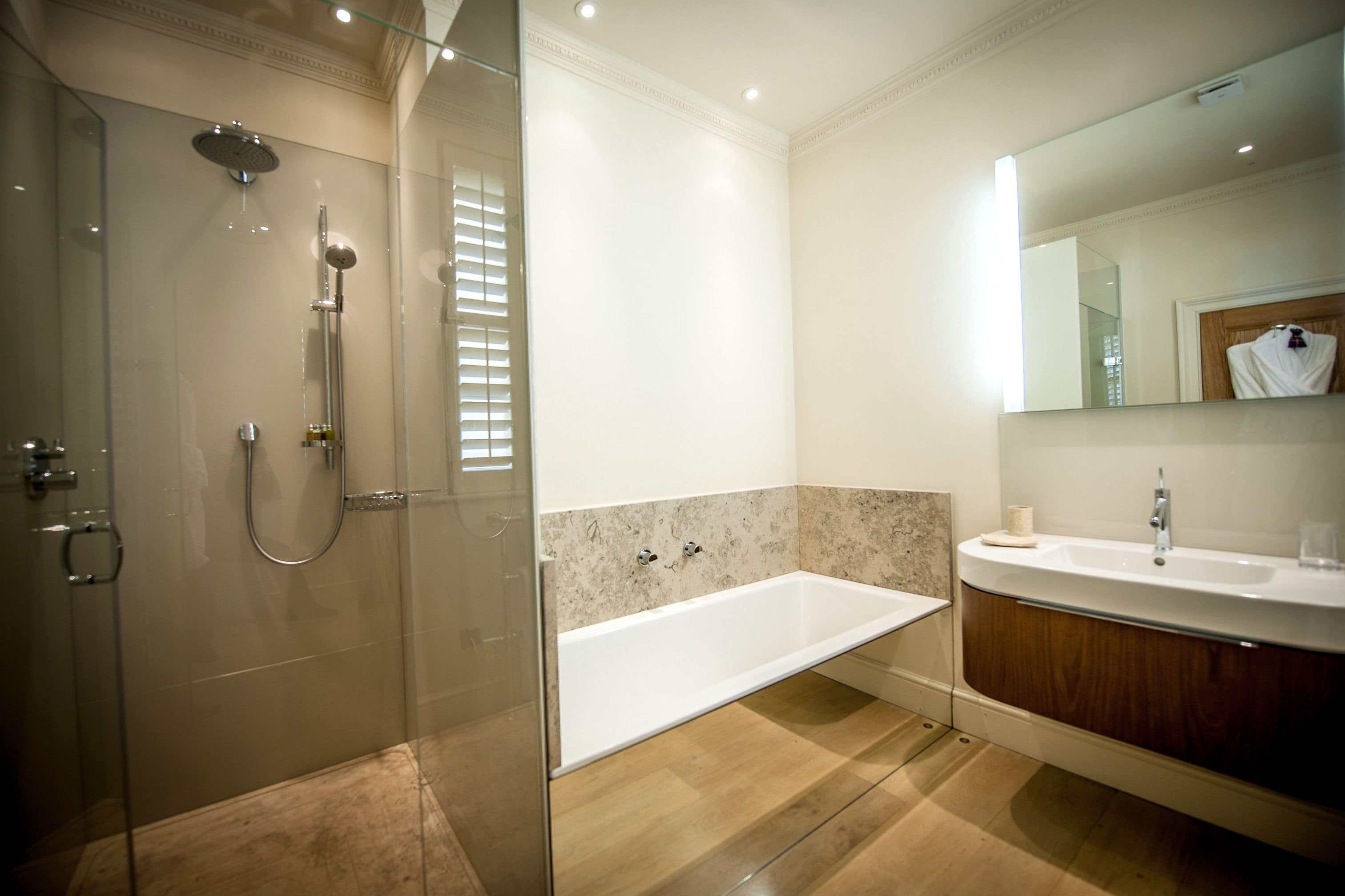 A modern bathroom with a glass-enclosed shower, a freestanding bathtub, and a vanity with a mirror.